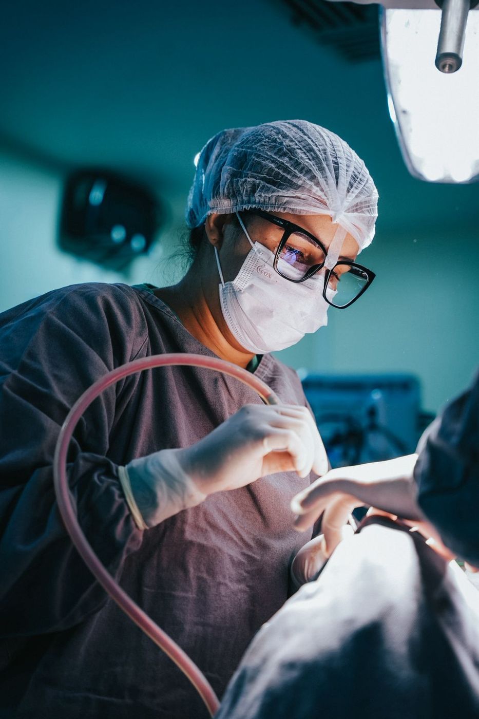 Cirurgiã em procedimento, com luvas e paramentação completa
